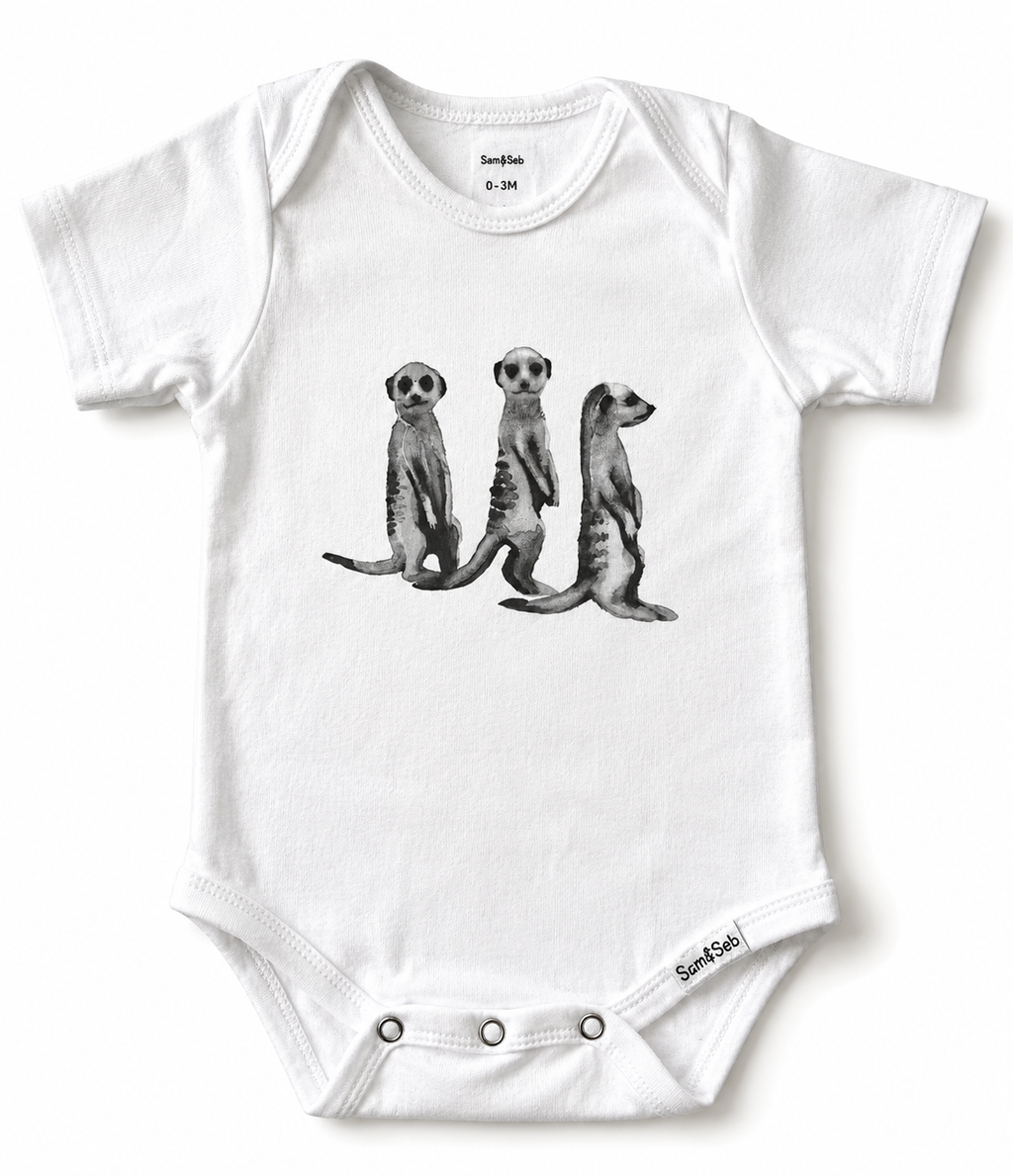 A white short-sleeve baby bodysuit featuring a black and white graphic print of three standing meerkats on the front. The brand name 'Sam & Seb' is visible on the inner neck label and near the bottom right corner.