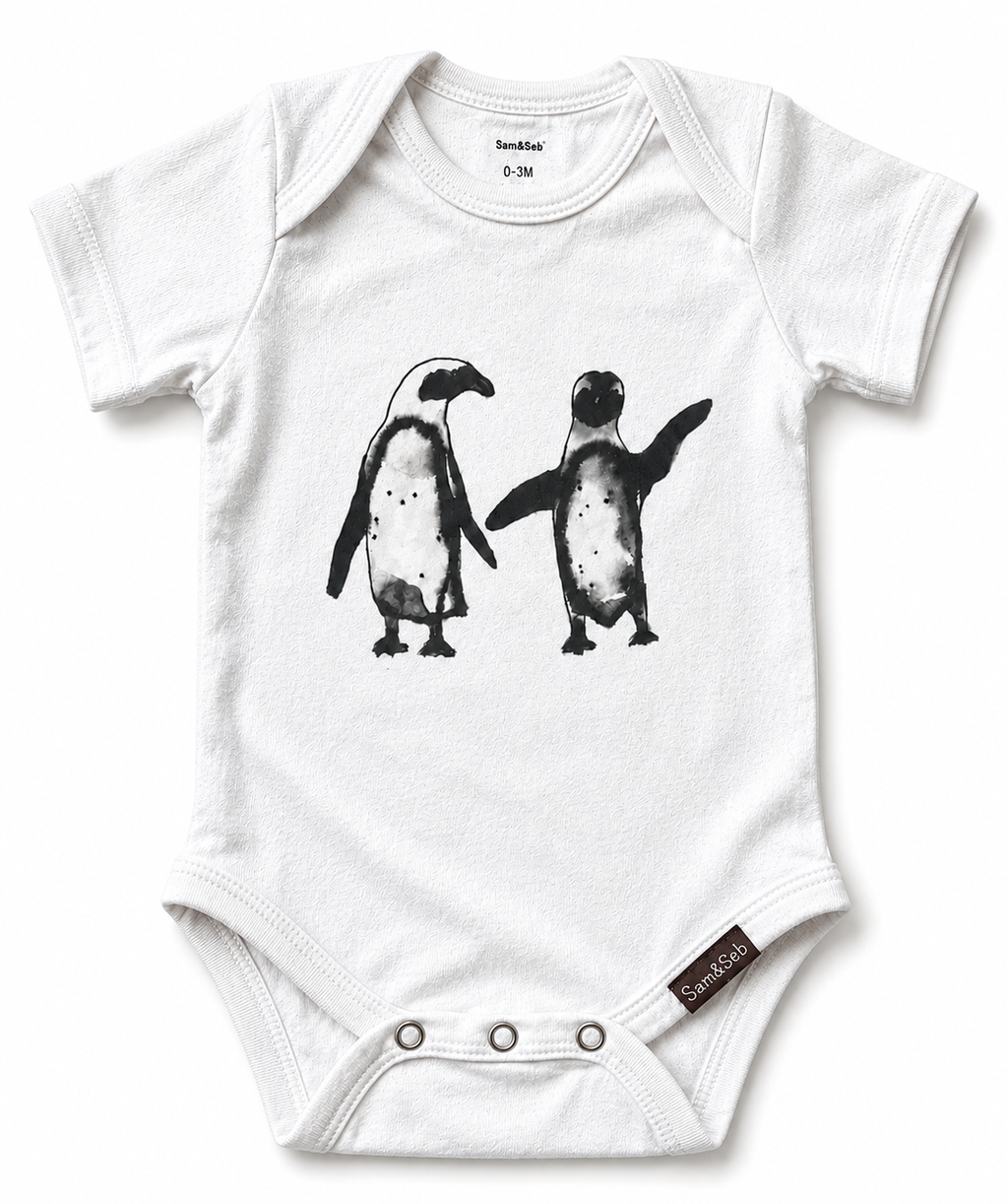 A white short-sleeve baby bodysuit featuring a black and white graphic print of two penguins on the front. The bodysuit has three snap closures at the crotch and a small brand tag near the bottom right.